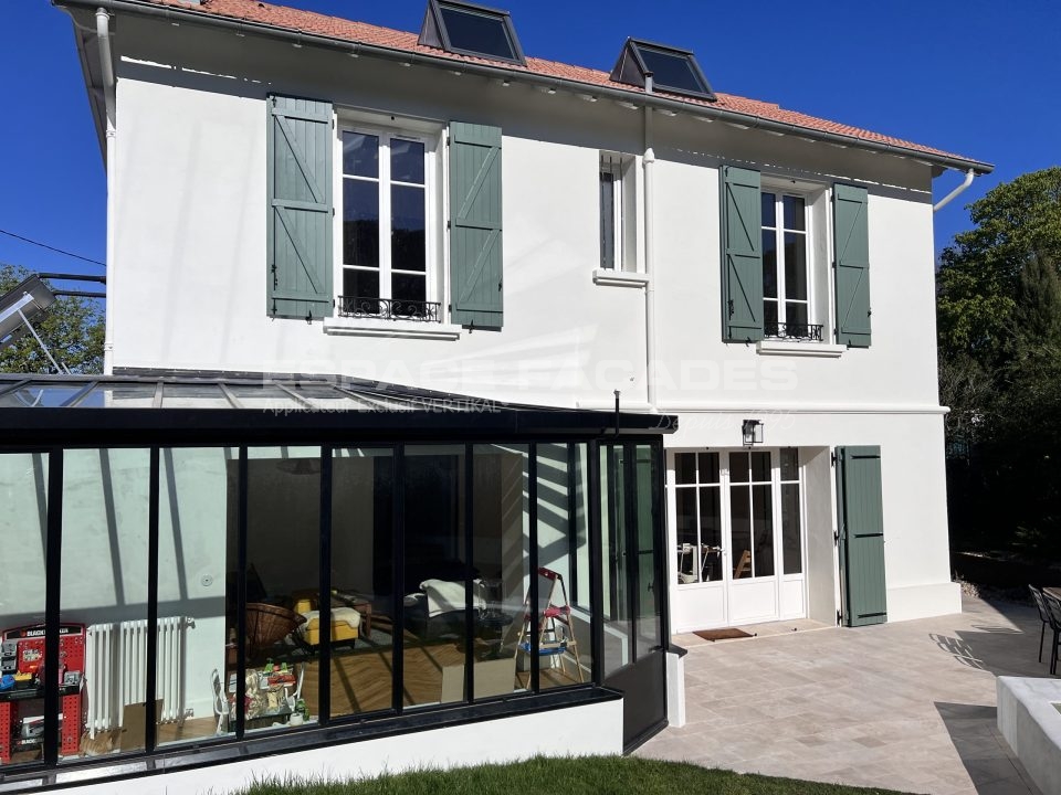 Maison avec une véranda moderne et façades blanches avec volets verts